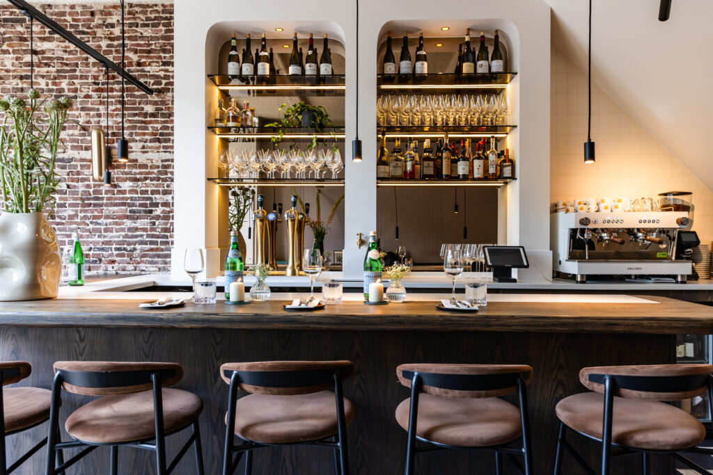 De bar met wijnglazen en gedekte plaatsen bij SOMM